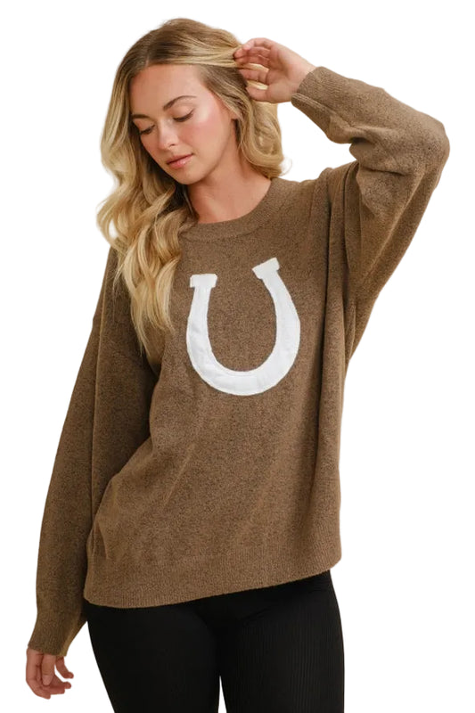 Woman wearing a brown horseshoe pullover sweater with a white horseshoe design on a beige background - equestrian fashion outfitters