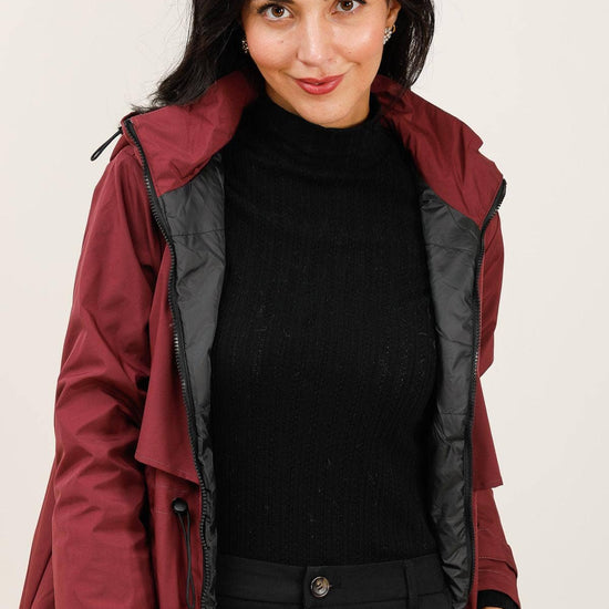 Woman wearing a red raincoat with a black interior on a plain background equestrian fashion outfitters