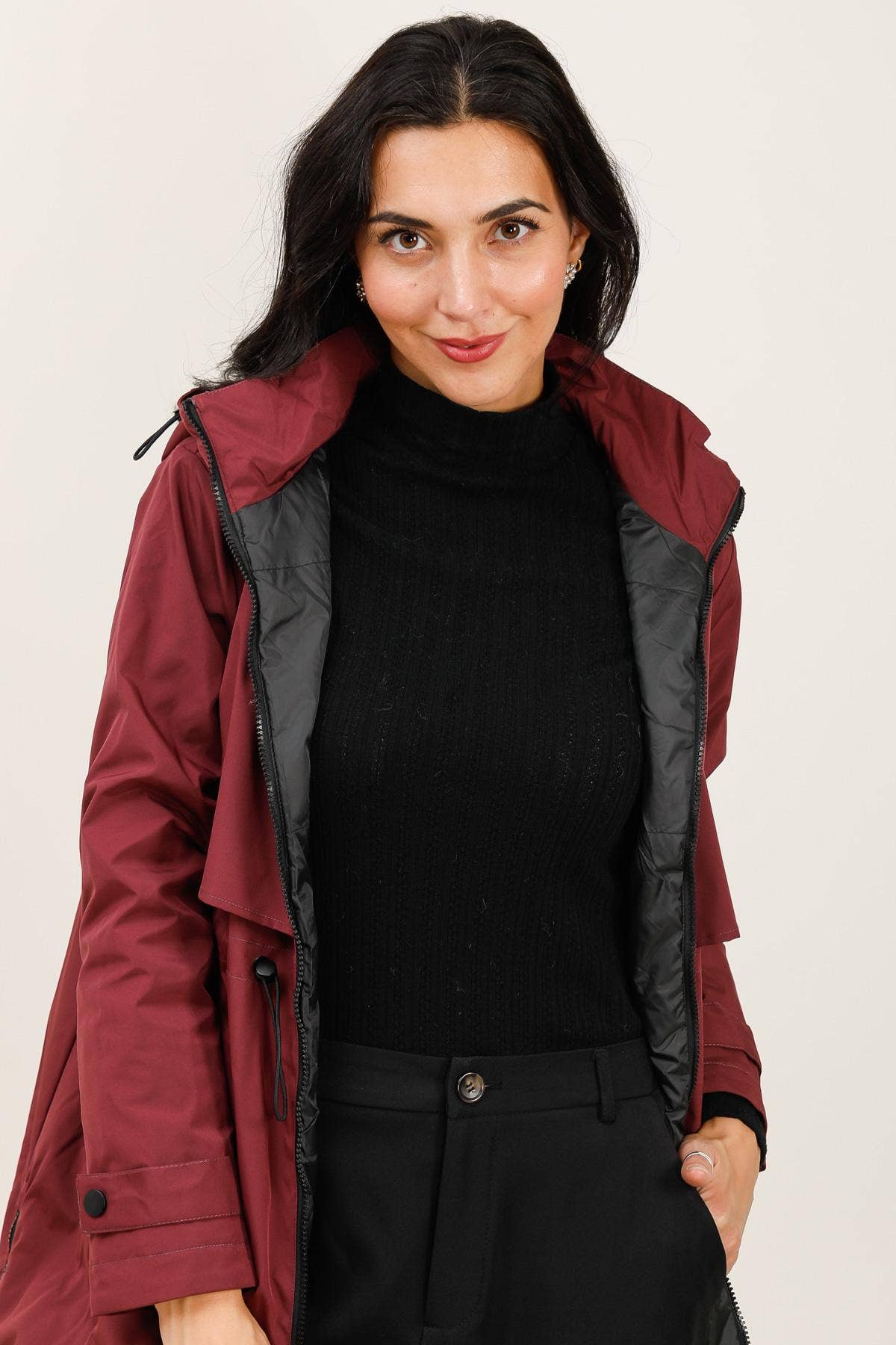 Woman wearing a red raincoat with a black interior on a plain background equestrian fashion outfitters