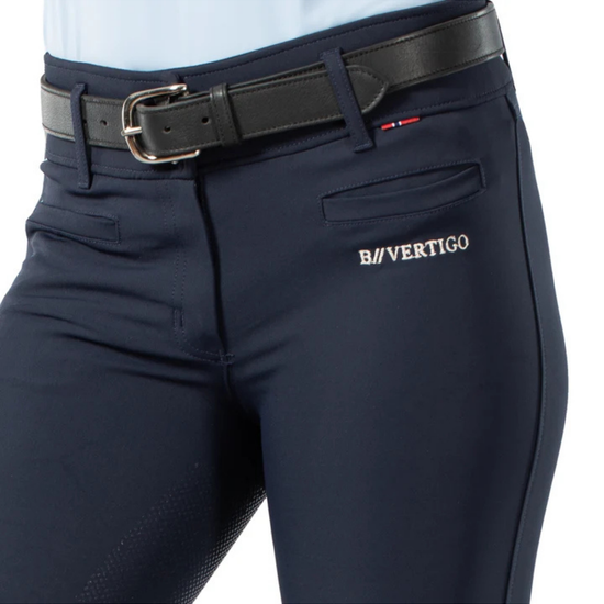 Close-up of navy blue equestrian riding breeches with a black leather belt, featuring the B/VERTIGO logo embroidered in white on the side pocket. equestrian fashion outfitters