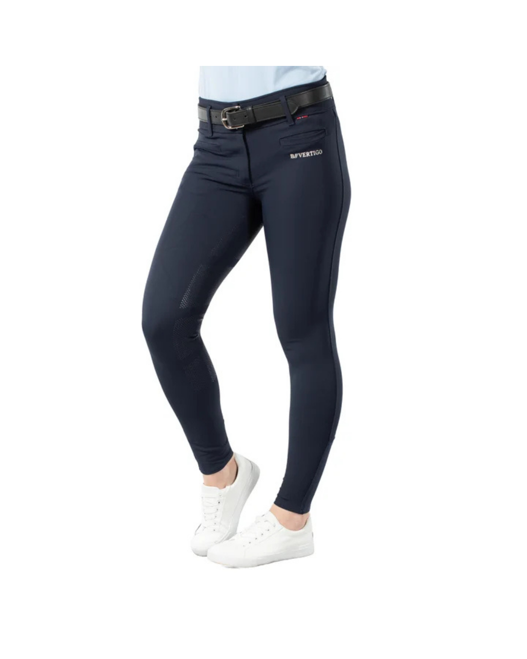 A person wearing navy fitted riding breeches with a black belt and white sneakers, shown from the waist down on a plain white background. A small white logo is visible on the upper right thigh. equestrian fashion outfitters