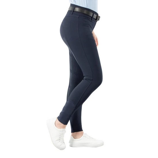 A person shown from the waist down wearing fitted navy breeches with a black belt, paired with white sneakers, on a plain white background. equestrian fashion outfitters