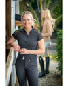 Woman wearing a black equestrian outfit with lace sleeves in an outdoor setting. kastel equestrian fashion outfitters