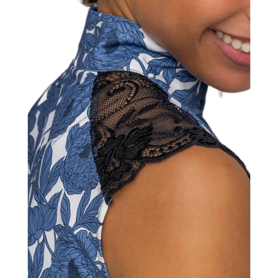 Close-up of a person wearing a blue floral shirt  with black lace detailing. Kastel equestrian fashion outfitters