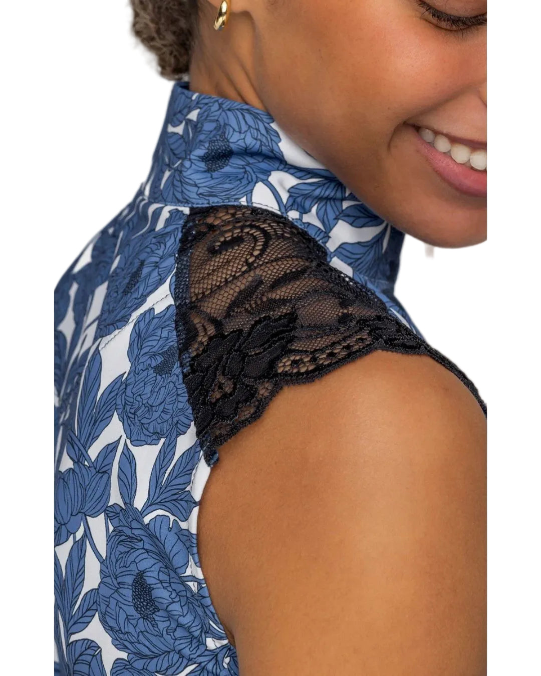 Close-up of a person wearing a blue floral shirt  with black lace detailing. Kastel equestrian fashion outfitters