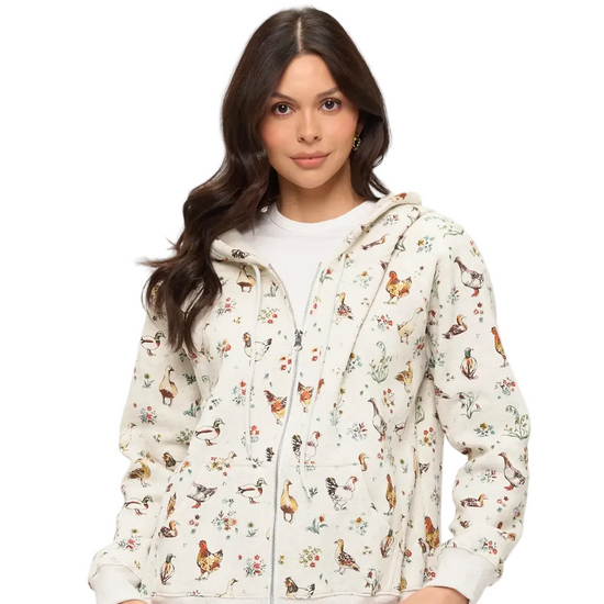 A woman wearing a white zip-up hoodie with a colorful all-over print of chickens, ducks, and small flowers, equestrian fashion outfitters