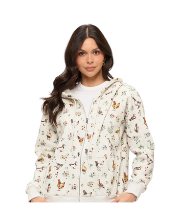A woman wearing a white zip-up hoodie with a colorful all-over print of chickens, ducks, and small flowers, equestrian fashion outfitters