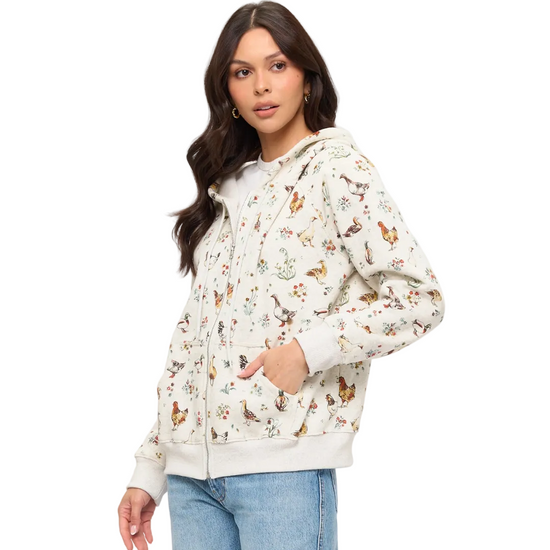 A woman modeling a cream-colored zip-up hoodie with chicken and flowers equestrian fashion outfitters