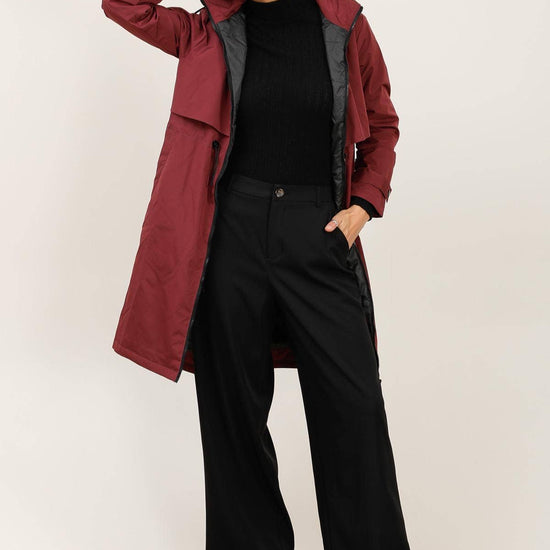 Woman wearing a burgundy coat over a black top and pants on a white background equestrian fashion outfitters