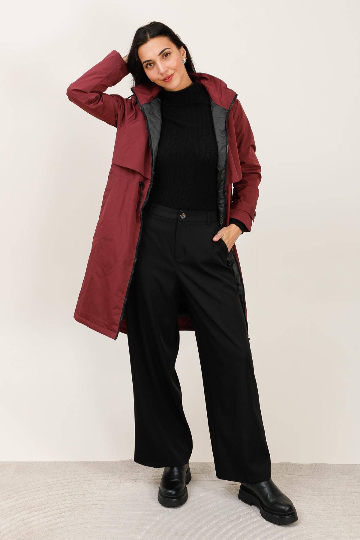 Woman wearing a burgundy coat over a black top and pants on a white background equestrian fashion outfitters