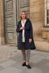 Woman wearing a navy coat standing in front of a stone building. equestrian fashion outfitters
