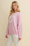Woman wearing a Pink horseshoe pullover sweater  on a beige background - equestrian fashion outfitters