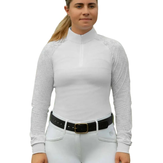 Woman wearing a white long-sleeve show shirt top and white pants with a black belt, standing outdoors. equestrian fashion outfitters