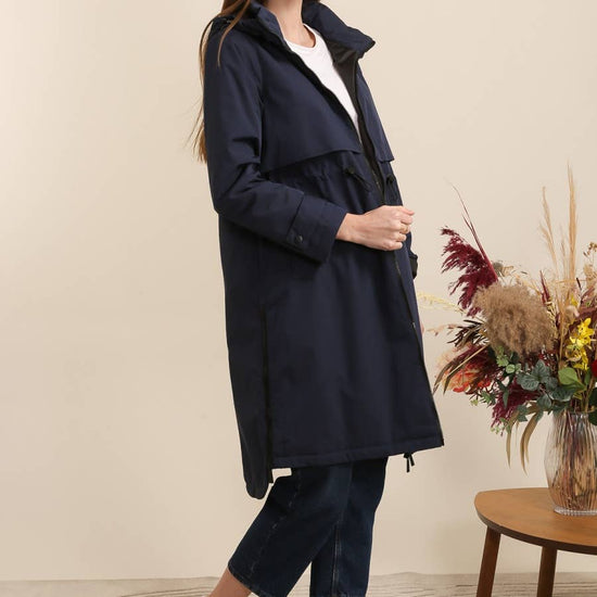 Woman wearing a navy coat standing in a room equestrian fashion outfitters 