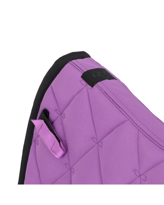 Close-up of a purple quilted padded cover with black trim and a small black brand patch, shown on a white background.equestrian fashion outfitters