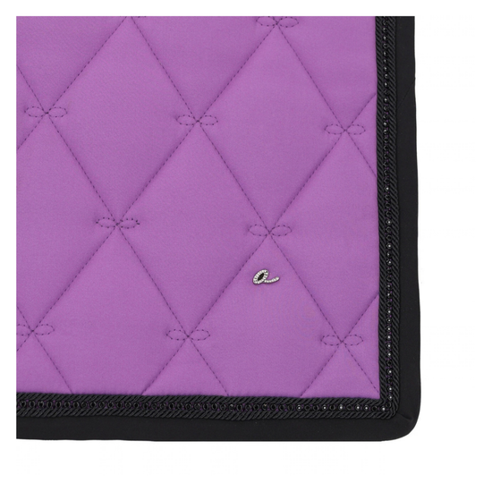 A close-up of a purple quilted fabric saddle pad featuring a diamond-quilted pattern, black braided trim, and a small silver embroidered script logo.equestrian fashion outfitters