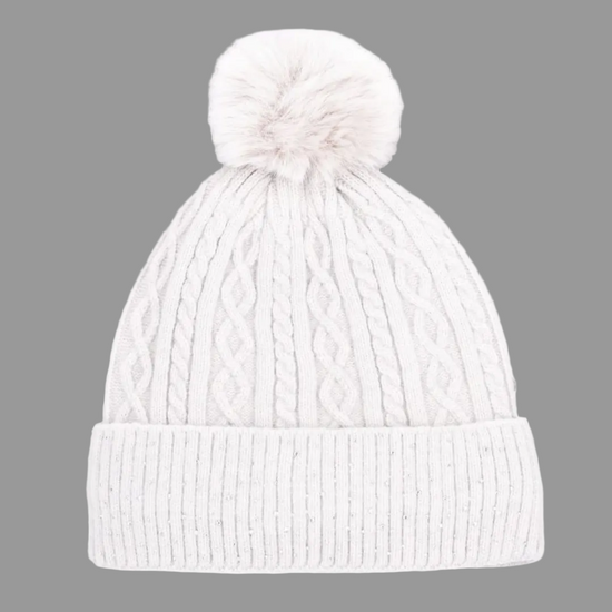 A white silver cable-knit beanie hat with a matching fluffy pom-pom on top and a ribbed folded cuff, shown against a plain white background. equestrian fashion outfitters